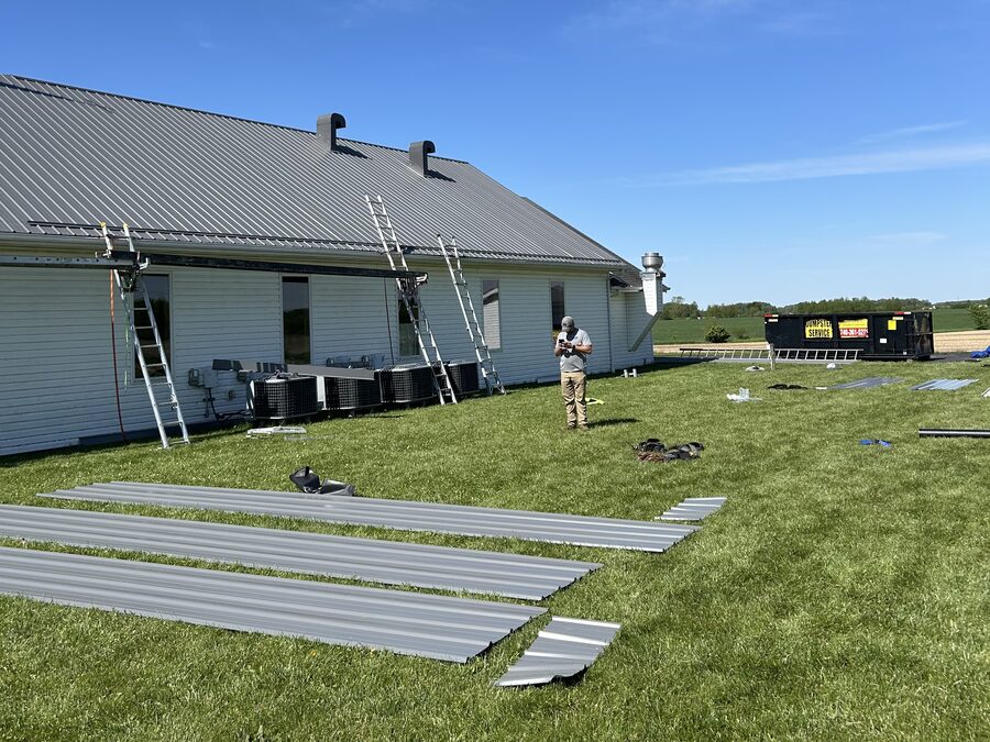 Metal roof panels staged and going on over a long low building